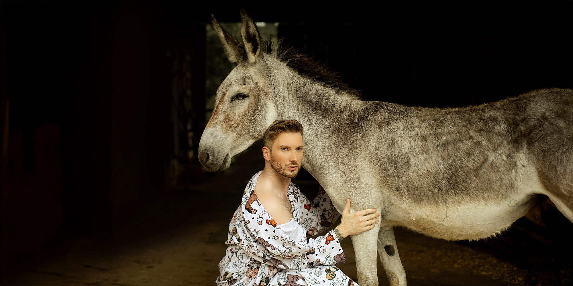 Matt Mathews crouching next to a donkey.