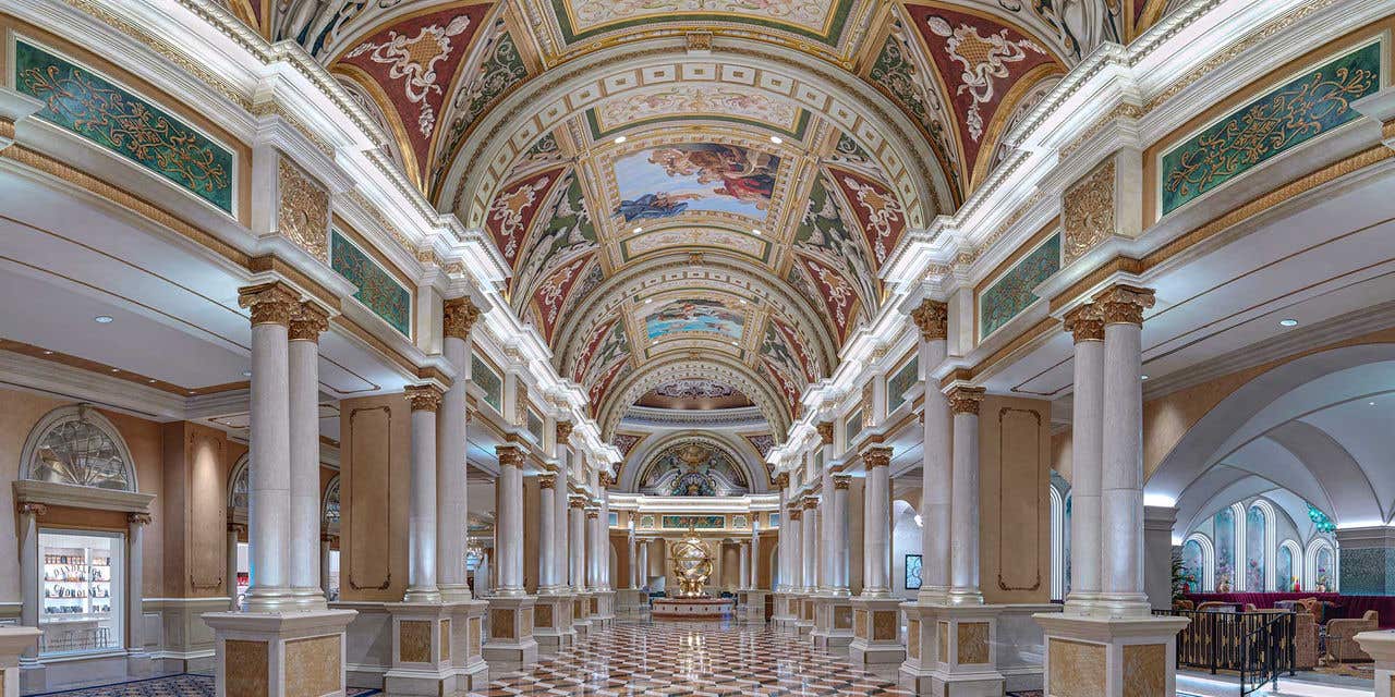 Grand hallway with tiled floors, fresco ceiling, and columns.