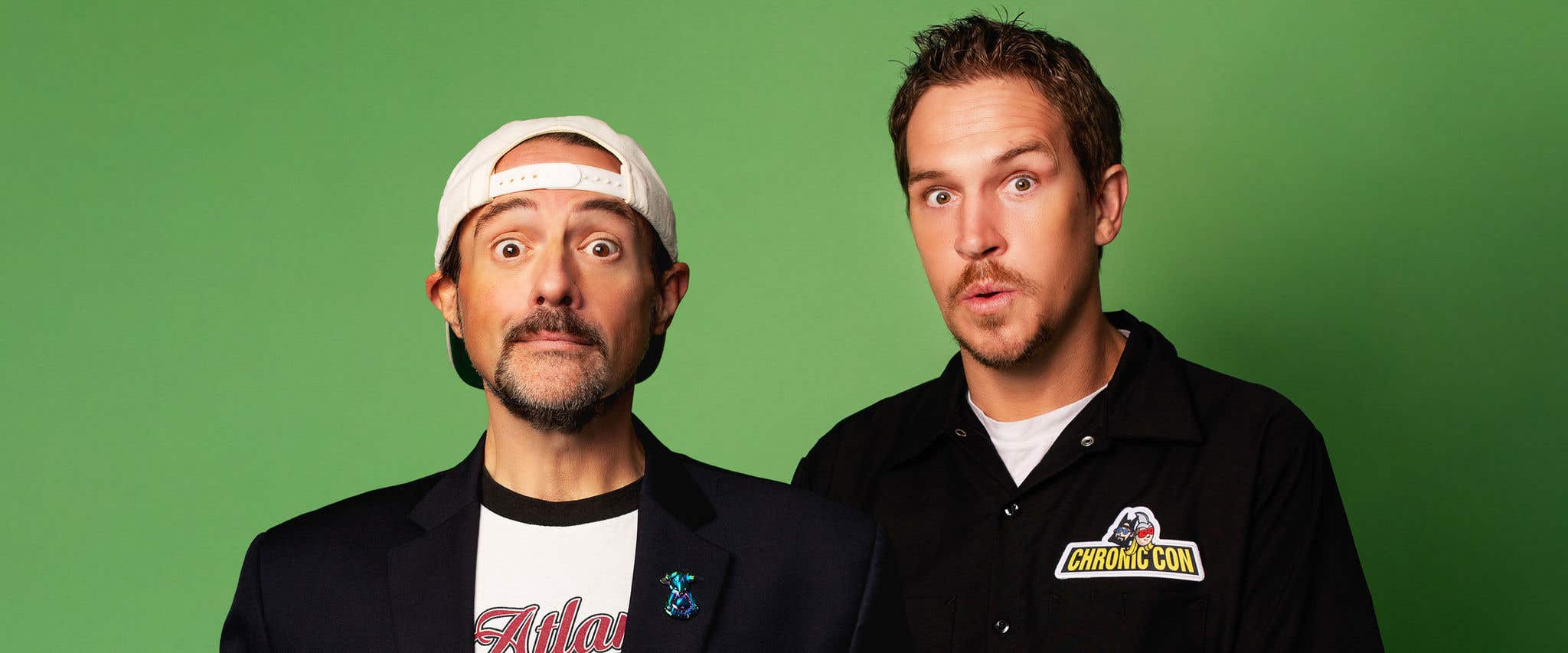 Jay & Silent Bob posing with surprised expressions in front of a green background.
