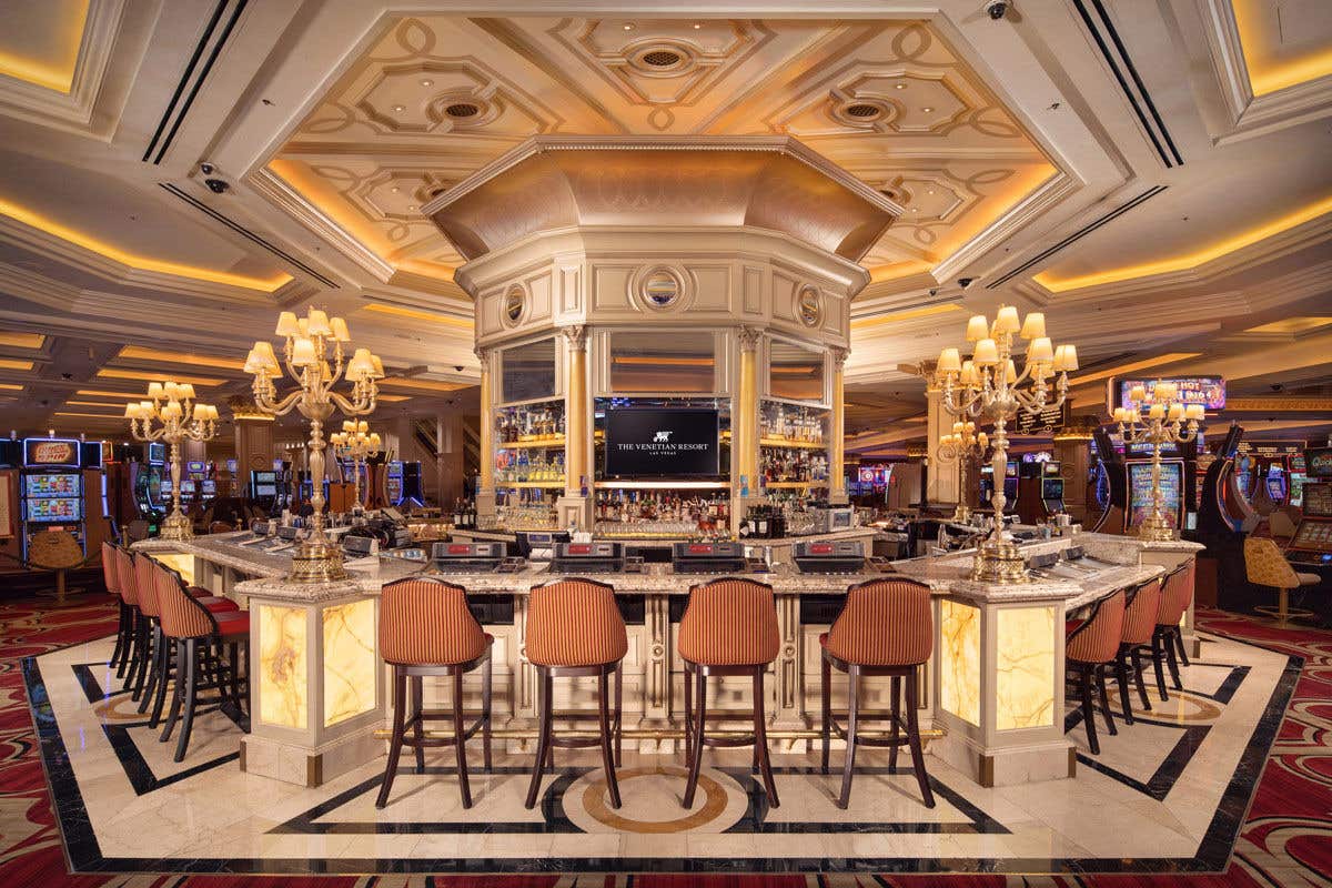 Bellini Bar with marble top, surrounded by plush barstools, chandeliers, and slot machines in the background.