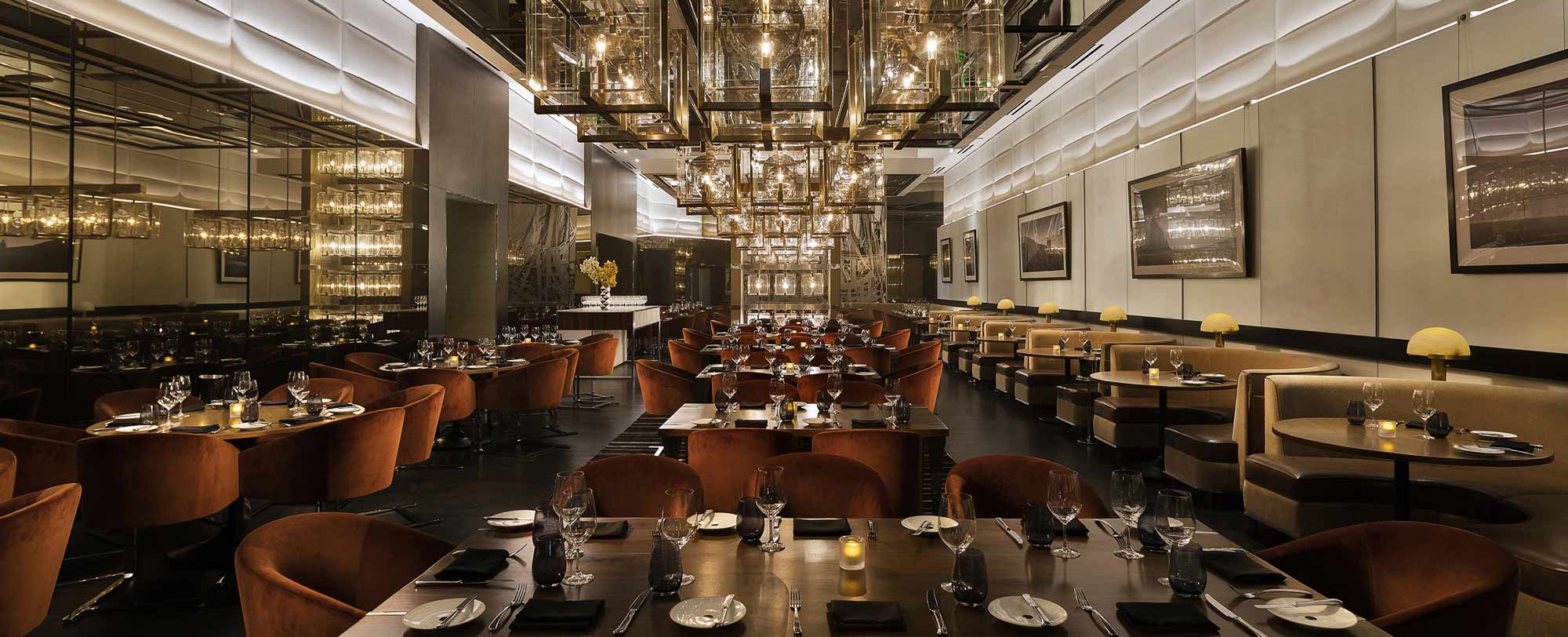 Luxurious restaurant interior featuring elegant lighting, plush velvet chairs, and beautifully set tables.