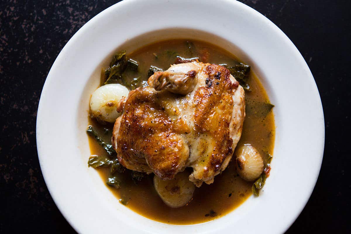 Half chicken in sauce with chunks of onions. 