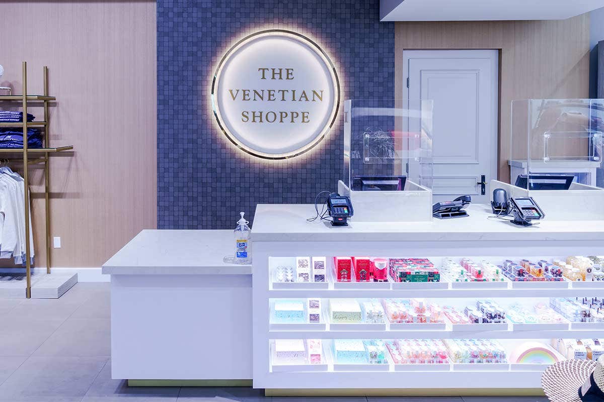 A gift shop counter with various items displayed and "The Venetian Shoppe" sign on the wall behind.