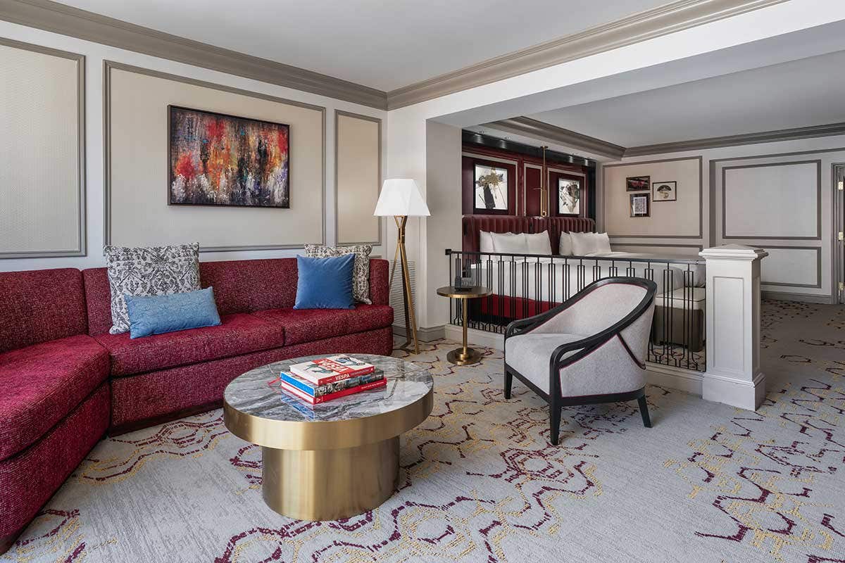 A hotel room with a living room area and two queen beds.