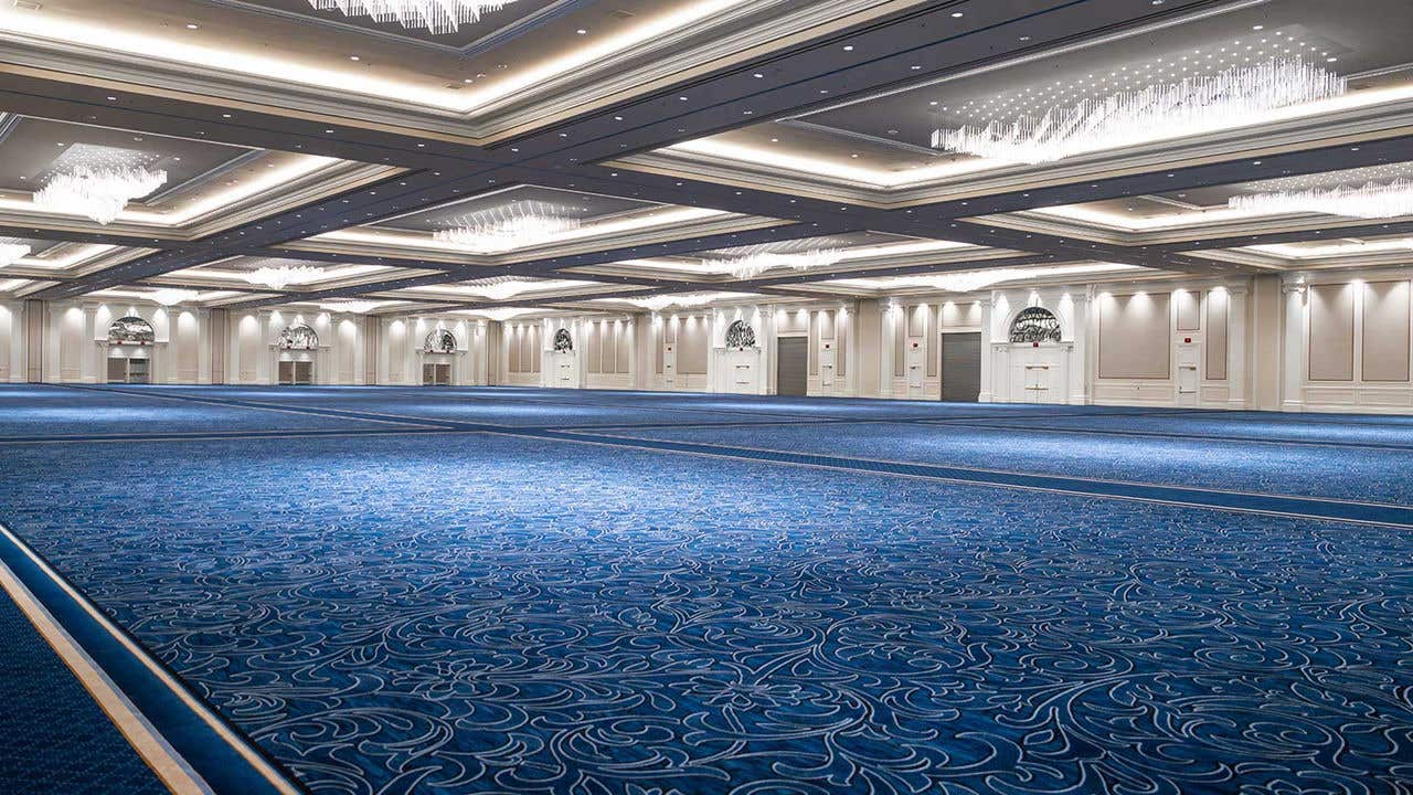 Large ballroom with blue carpet and chandelier above.