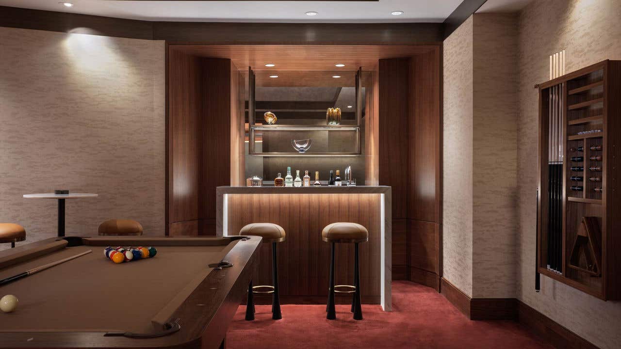 A billiard room with a pool table, wet bar, and bar seating.