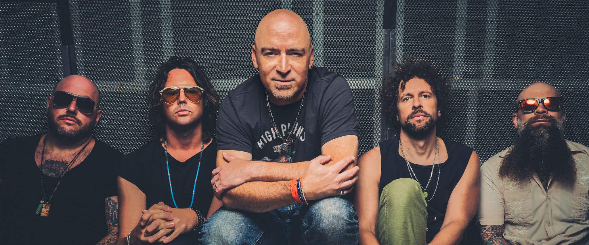 Live band members sitting on the floor and staring directly at the camera.