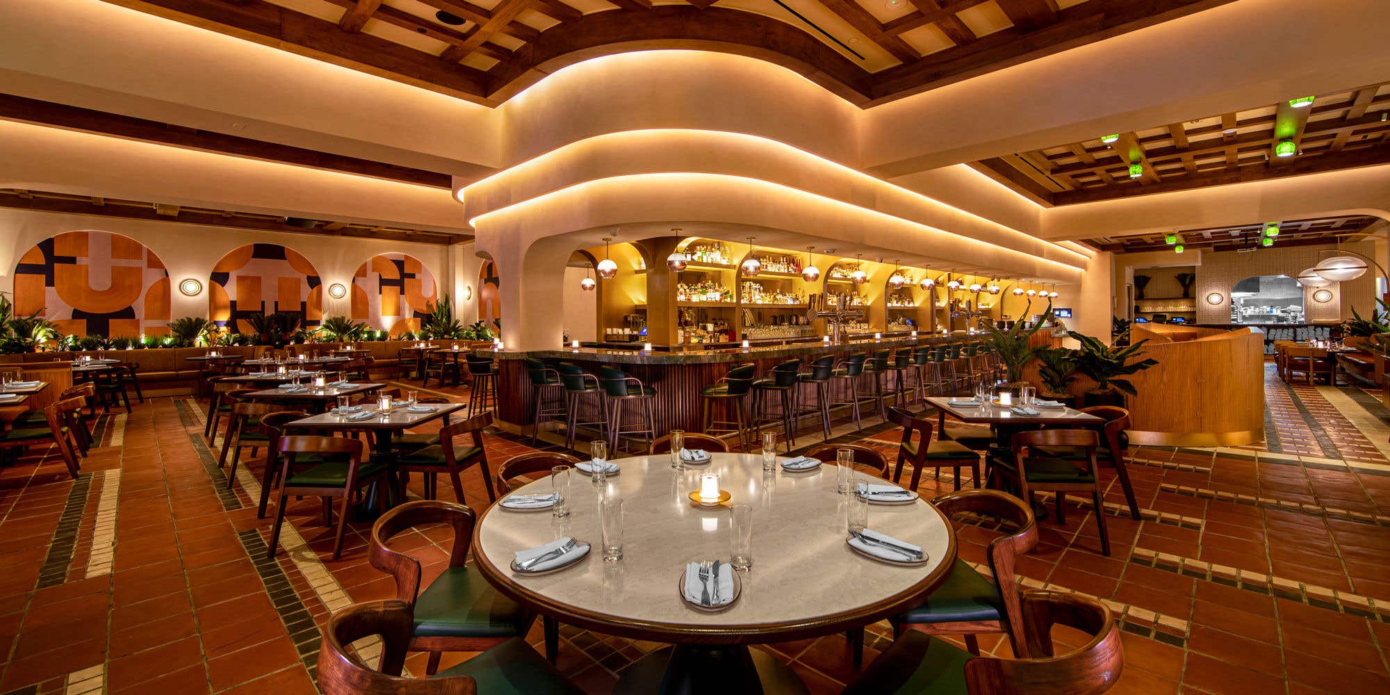 Interior of Las Vegas restaurant Sugarcane, showing a center bar and dark wood tables with green accents.